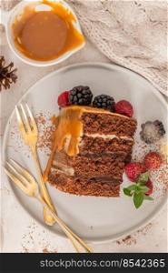 Delicious semi-naked chocolate cake with caramel topping and decorated with blackberries and raspberries. Light background