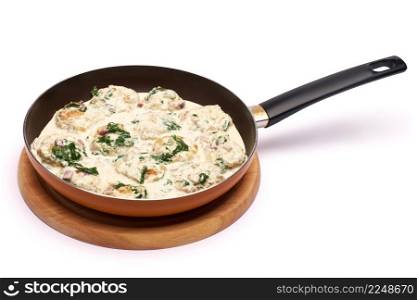 Delicious small meatballs with spinach in a creamy sauce in the frying pan. High quality photo. Delicious small meatballs with spinach in a creamy sauce in the frying pan