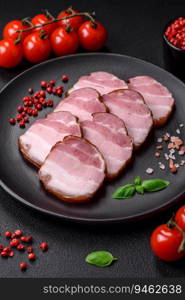 Delicious smoked bacon with salt, spices and herbs on a dark concrete background