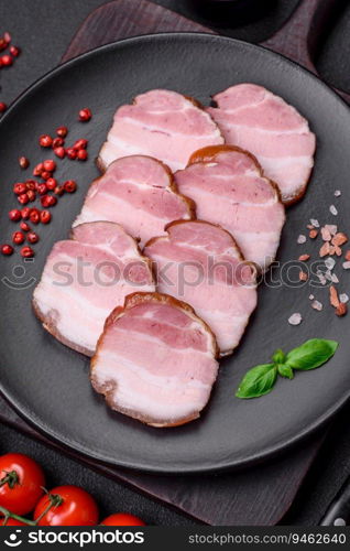 Delicious smoked bacon with salt, spices and herbs on a dark concrete background