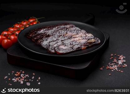 Delicious smoked or cured mahan horse meat sausage with spices and herbs on a dark concrete background