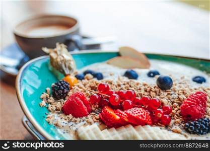 Delicious smoothie bowl with strawberries, banana, blueberries, apple and granola on summer background. Breakfast bowl with fruit and cereal, close-up, top view, space for text