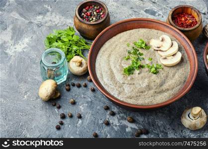 Delicious soup puree with champignons and fresh mushrooms on rustic table. Creamy mushroom soup
