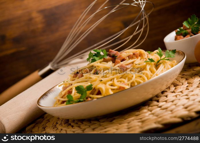 Delicious spaghetti with bacon and egg called alla carbonara on wooden table