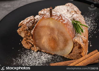 Delicious spice cake with pear, ginger and cinnamon on a dark kitchen counter.