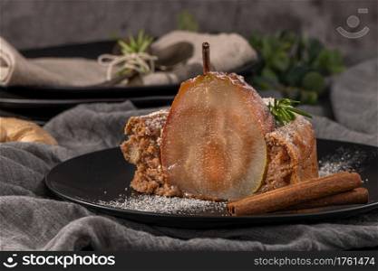 Delicious spice cake with pear, ginger and cinnamon on a dark kitchen counter.