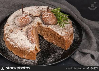 Delicious spice cake with pear, ginger and cinnamon on a dark kitchen counter.