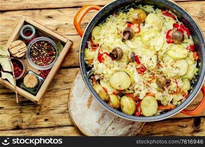 Delicious stewed vegetables in pan,healthy vegetarian food. Vegetable saute on wooden table