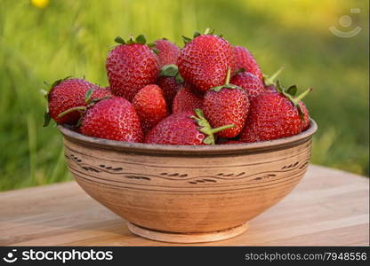 Delicious strawberries in a clay bowl in nature . A bowl of strawberries