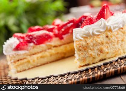 delicious strawberry cake with cream on wooden table