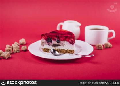 delicious strawberry jelly cheese cake white plate with brown sugar cubes against red backdrop