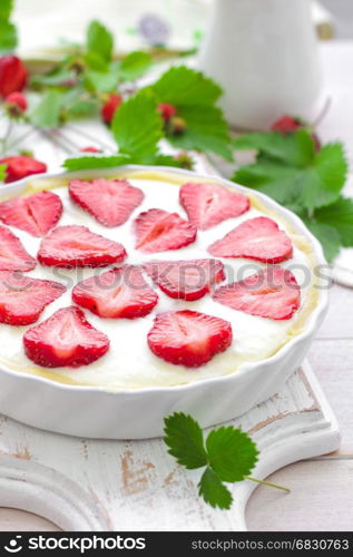 Delicious strawberry tart or cheesecake with fresh berries and cream cheese, closeup on white wooden rustic background