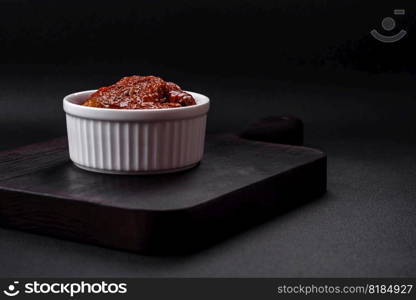 Delicious sun dried tomatoes in oil in a white ceramic bowl on a dark concrete background