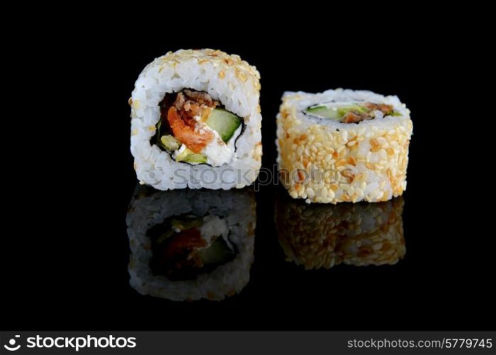 Delicious sushi rolls on black background