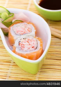 Delicious sushi served with chopsticks and soy sauce, tasty roll with crab meat and raw salmon, traditional asian food, healthy eating concept