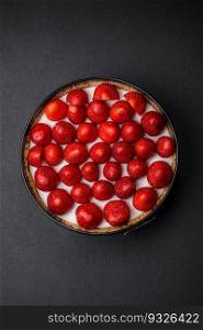Delicious sweet cake or cheesecake with mascarpone cheese and strawberries on a dark concrete background