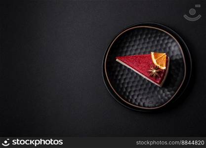 Delicious sweet cheesecake with raspberry jam on a black ceramic plate on a dark concrete background