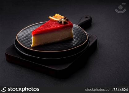 Delicious sweet cheesecake with raspberry jam on a black ceramic plate on a dark concrete background