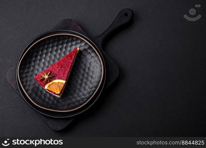 Delicious sweet cheesecake with raspberry jam on a black ceramic plate on a dark concrete background