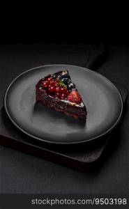 Delicious sweet chocolate brownie cake with blueberries, currants and raspberries on a ceramic plate