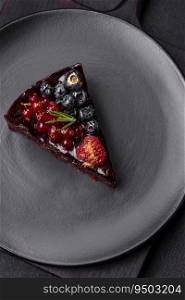 Delicious sweet chocolate brownie cake with blueberries, currants and raspberries on a ceramic plate