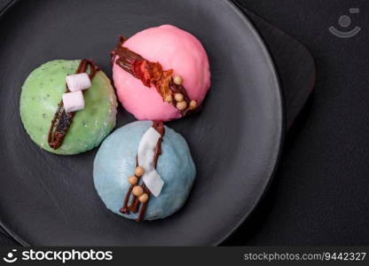 Delicious sweet colorful mochi desserts or ice cream with rice dough and toppings on a dark concrete background