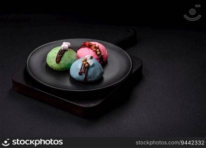 Delicious sweet colorful mochi desserts or ice cream with rice dough and toppings on a dark concrete background