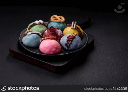 Delicious sweet colorful mochi desserts or ice cream with rice dough and toppings on a dark concrete background