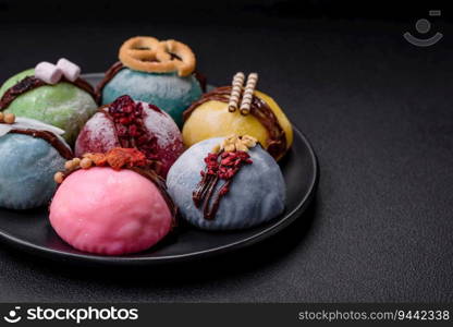 Delicious sweet colorful mochi desserts or ice cream with rice dough and toppings on a dark concrete background