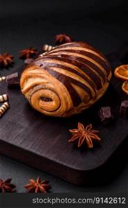 Delicious sweet crispy fresh baked cinnamon bun on dark concrete background