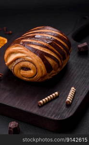 Delicious sweet crispy fresh baked cinnamon bun on dark concrete background