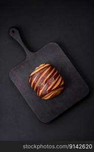 Delicious sweet crispy fresh baked cinnamon bun on dark concrete background