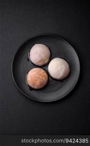 Delicious sweet mochi dessert with toppings on a dark concrete background. Nutritious vegetarian Asian dessert