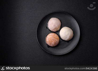 Delicious sweet mochi dessert with toppings on a dark concrete background. Nutritious vegetarian Asian dessert