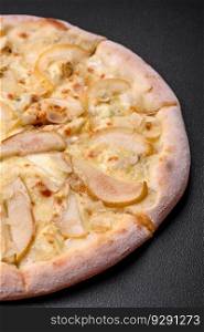 Delicious sweet pizza with pear, dorblu cheese and nuts on a dark concrete background