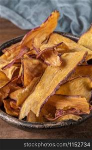 Delicious sweet potato chips in bowl, on table.