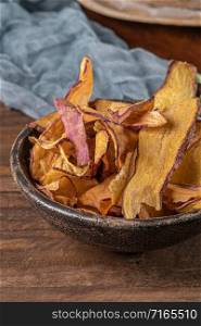 Delicious sweet potato chips in bowl, on table.