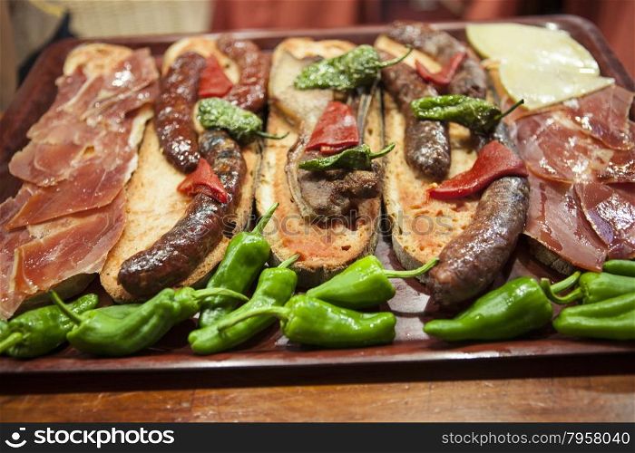 Delicious Tapas with Smoked Jamon on Garlic Bread with Greens, Olive Oil and Green Olives.
