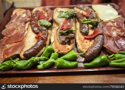 Delicious Tapas with Smoked Jamon on Garlic Bread with Greens, Olive Oil and Green Olives.