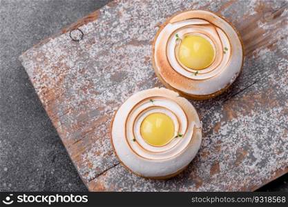 Delicious tart with citrus filling and walnut cream on a textured concrete background