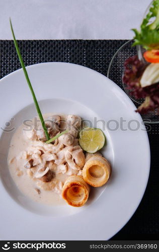 Delicious tender chicken breast with fresh italian creamy white wine mushroom sauce and puff pastry in white plate on dinner table. Top view shot