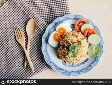 Delicious Thai fried rice with wooden spoon on tablecloth