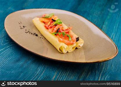 Delicious thin pancakes with salmon and sour cream on plate