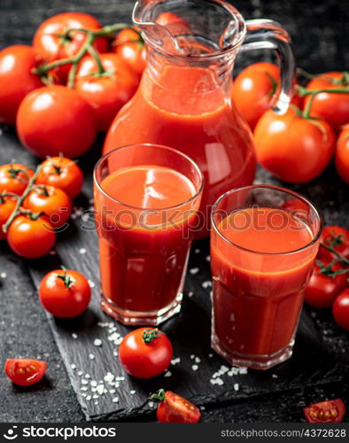 Delicious tomato juice in shots. On a black background. High quality photo. Delicious tomato juice in shots .