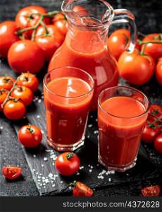 Delicious tomato juice in shots. On a black background. High quality photo. Delicious tomato juice in shots .