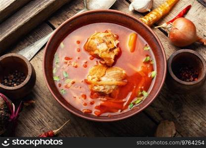 Delicious Ukrainian red borscht in a plate on a rustic old wooden table. Red Ukrainian borscht