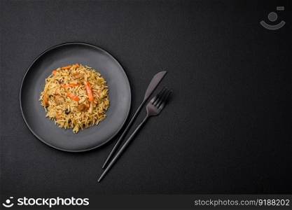 Delicious Uzbek pilaf with chicken, carrots, barberry, spices and herbs on a dark concrete background