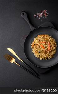 Delicious Uzbek pilaf with chicken, carrots, barberry, spices and herbs on a dark concrete background