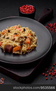 Delicious Uzbek pilaf with chicken, carrots, barberry, spices and herbs on a dark concrete background