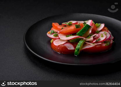 Delicious vegan salad of fresh vegetables of tomatoes, cucumbers and radishes with salt and spices on a dark concrete background